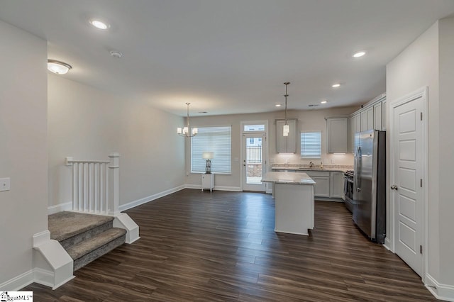 kitchen with a sink, dark wood-style flooring, freestanding refrigerator, and a kitchen island