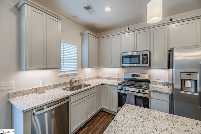 kitchen featuring visible vents, a sink, light stone countertops, stainless steel appliances, and dark wood-style flooring