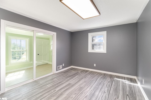 unfurnished room featuring visible vents, baseboards, wood finished floors, and ornamental molding