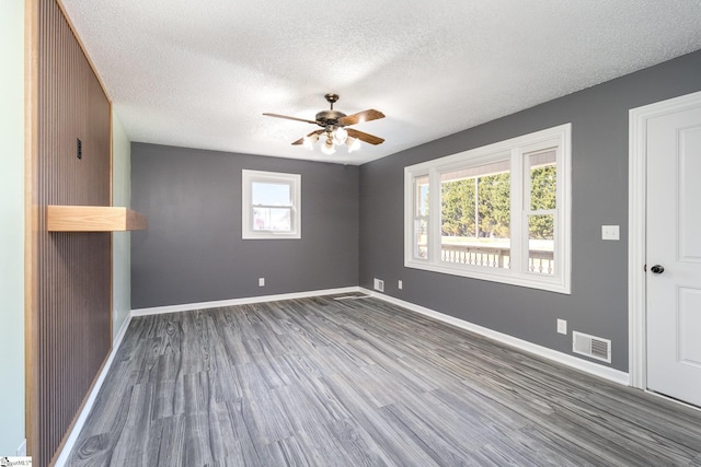 spare room with wood finished floors, visible vents, baseboards, ceiling fan, and a textured ceiling