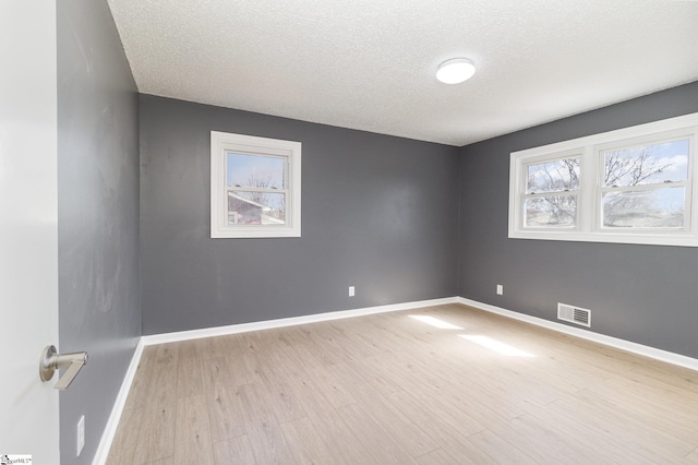 empty room featuring light wood-style flooring, baseboards, and visible vents