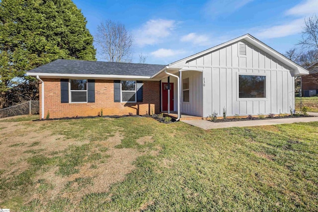 view of front of property featuring brick siding, board and batten siding, a front lawn, and fence