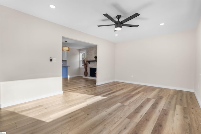 unfurnished living room with light wood-style flooring, recessed lighting, a fireplace, and baseboards