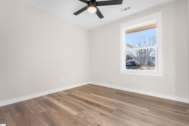 spare room with visible vents, baseboards, and wood finished floors