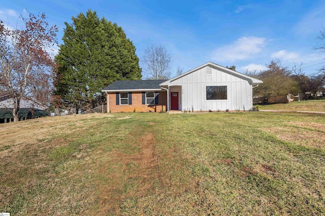 view of front of property with brick siding, a front yard, fence, and board and batten siding