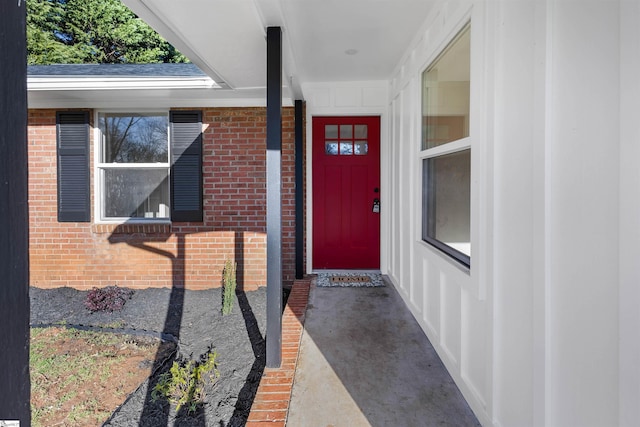 entrance to property featuring brick siding and a shingled roof