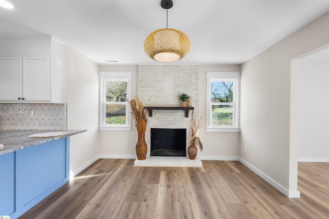 unfurnished living room featuring a healthy amount of sunlight, a fireplace, and light wood-type flooring