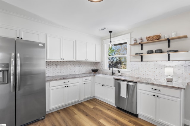 kitchen featuring light wood-type flooring, visible vents, white cabinetry, appliances with stainless steel finishes, and decorative backsplash