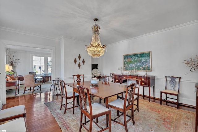 dining room featuring a notable chandelier, ornamental molding, and wood finished floors