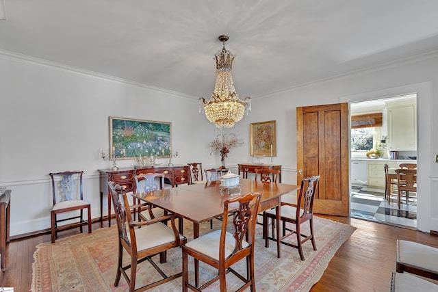 dining space featuring a notable chandelier, ornamental molding, and wood finished floors