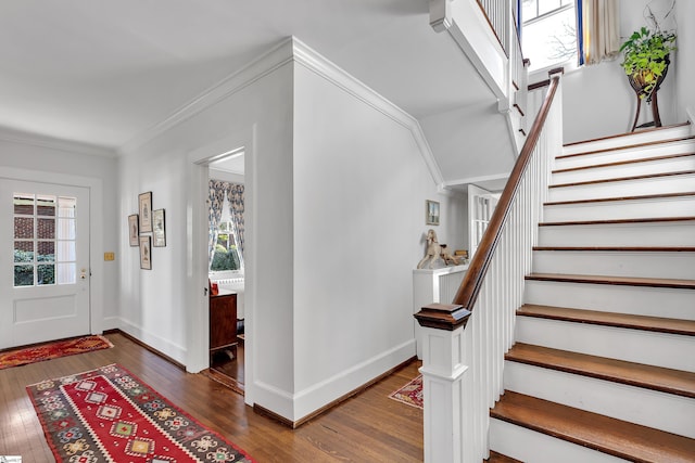 foyer entrance featuring hardwood / wood-style floors, crown molding, stairs, and baseboards