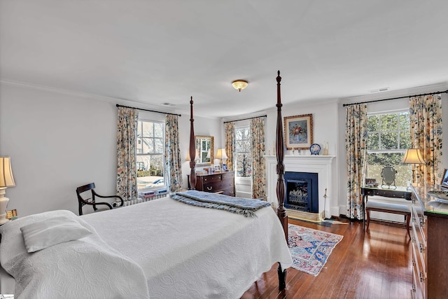 bedroom featuring visible vents, multiple windows, crown molding, and wood finished floors