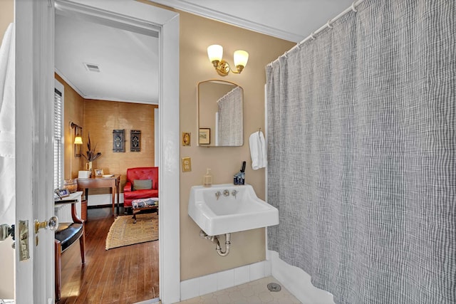 bathroom featuring crown molding, wood finished floors, visible vents, and a sink