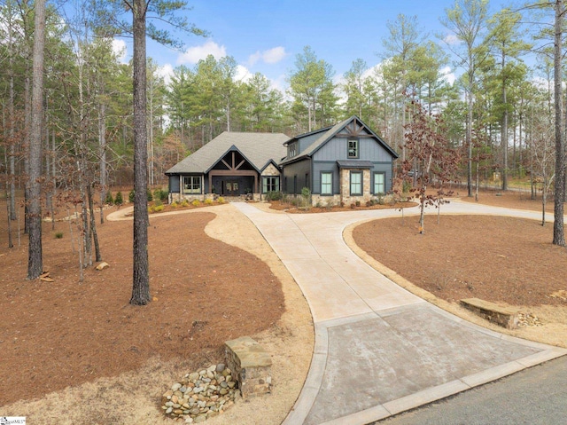 view of front facade featuring stone siding, curved driveway, and board and batten siding