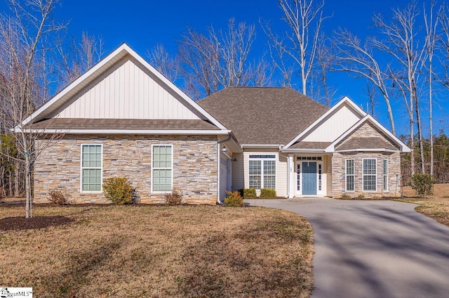 view of front of home featuring board and batten siding, a front yard, stone siding, and roof with shingles