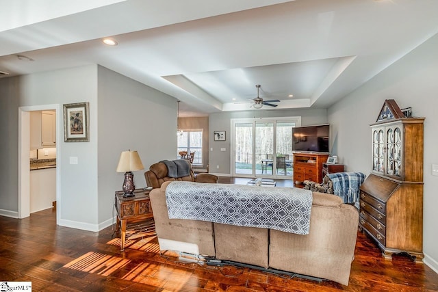 living area with recessed lighting, a raised ceiling, baseboards, and wood finished floors