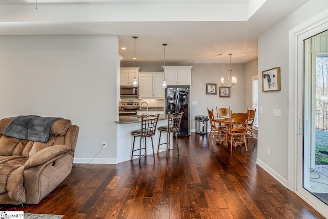 interior space with a chandelier, plenty of natural light, baseboards, and dark wood-style flooring