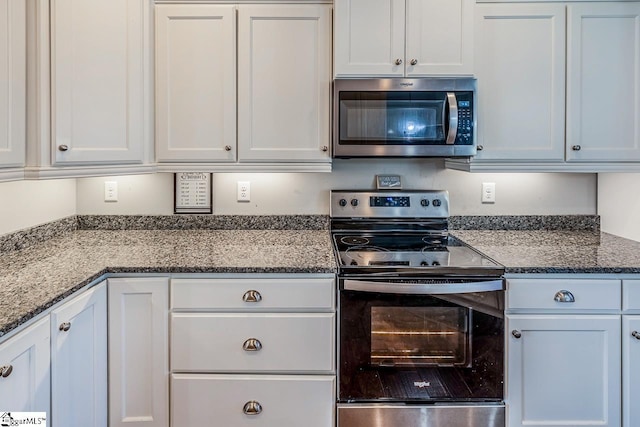 kitchen with white cabinetry, dark stone countertops, and stainless steel appliances