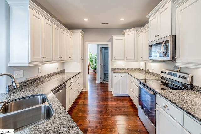 kitchen with visible vents, a sink, appliances with stainless steel finishes, white cabinets, and dark wood-style flooring