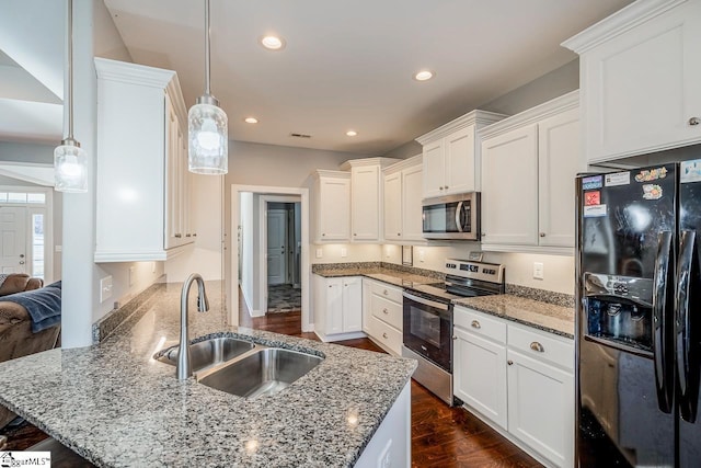 kitchen with light stone counters, a peninsula, white cabinets, stainless steel appliances, and a sink