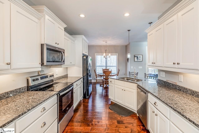 kitchen with dark wood-type flooring, white cabinets, appliances with stainless steel finishes, and a sink