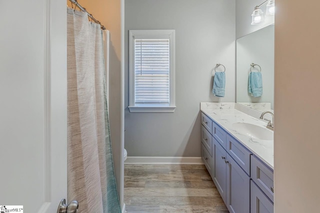 bathroom featuring toilet, vanity, baseboards, and wood finished floors