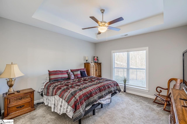 bedroom featuring baseboards, visible vents, carpet floors, a tray ceiling, and ceiling fan