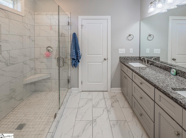 bathroom featuring baseboards, double vanity, a sink, a shower stall, and marble finish floor