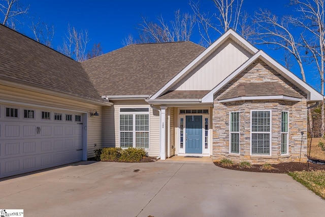 view of front of house featuring stone siding, an attached garage, driveway, and roof with shingles