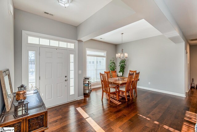 foyer entrance featuring visible vents, baseboards, dark wood-type flooring, and a notable chandelier