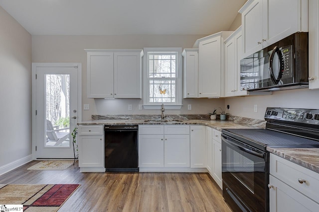 kitchen with black appliances, white cabinets, light wood finished floors, and a sink