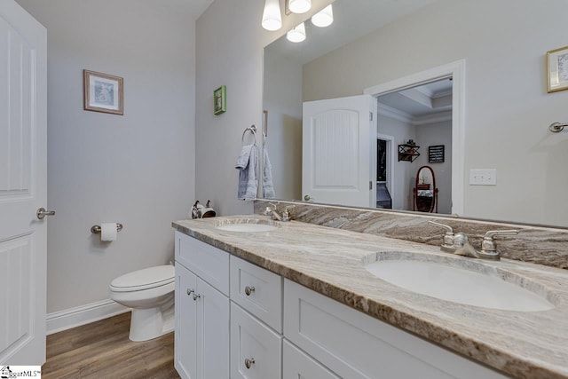 full bath with a sink, toilet, wood finished floors, and double vanity