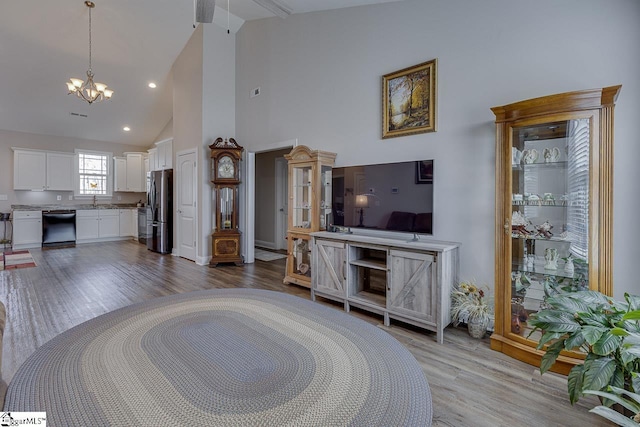 living area featuring high vaulted ceiling, recessed lighting, light wood-style floors, and a chandelier