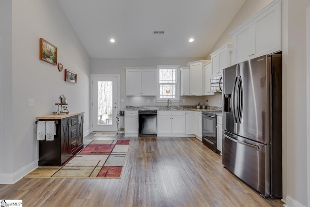 kitchen featuring lofted ceiling, light wood-style floors, and black appliances