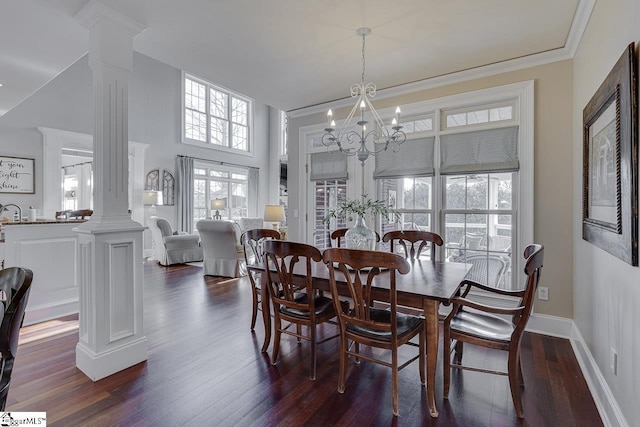 dining space with baseboards, ornate columns, dark wood finished floors, ornamental molding, and a notable chandelier