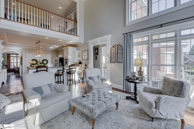 living room with arched walkways, ornamental molding, baseboards, and wood finished floors