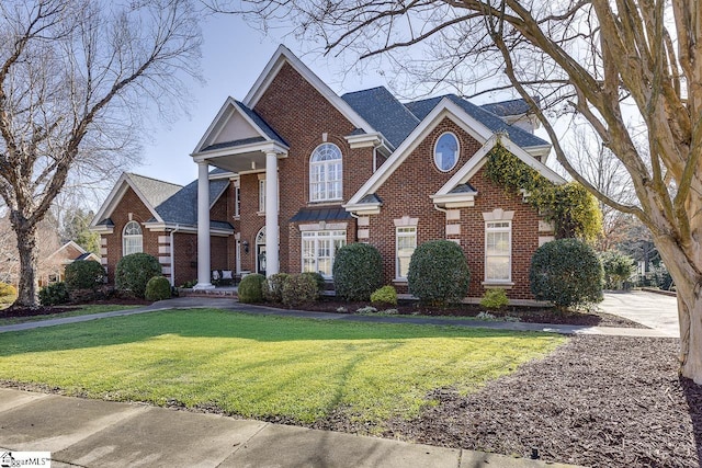 view of front of house with brick siding, a front yard, and a shingled roof