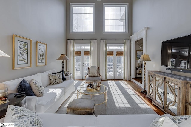 living area with wood finished floors, french doors, and a towering ceiling