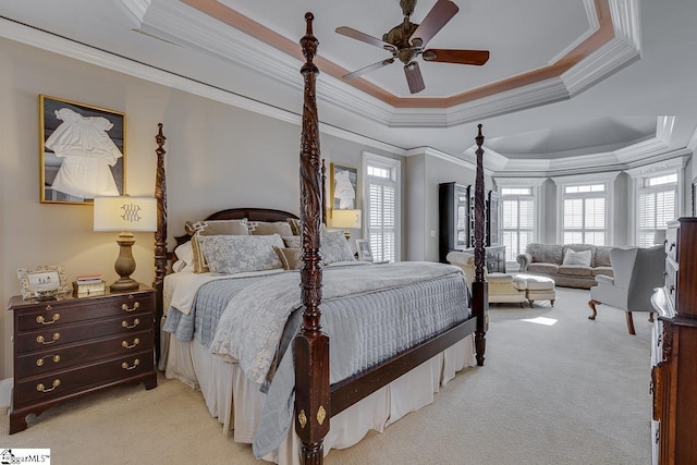 bedroom featuring light colored carpet, crown molding, a tray ceiling, and ceiling fan