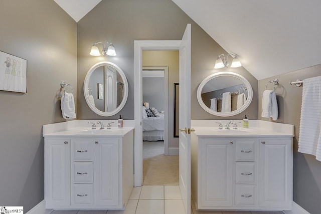 bathroom featuring two vanities, lofted ceiling, and a sink