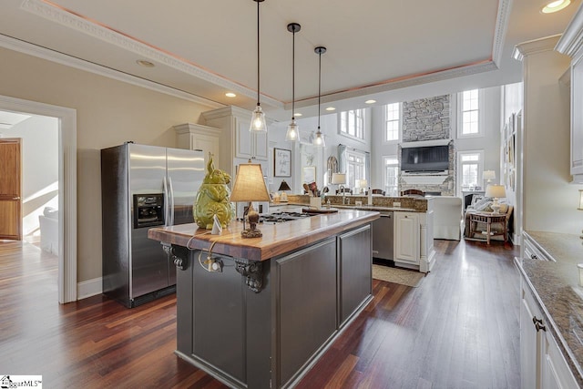 kitchen with a center island, open floor plan, appliances with stainless steel finishes, and ornamental molding