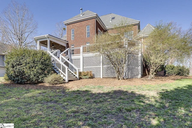 rear view of house featuring a lawn, a deck, a ceiling fan, stairway, and brick siding