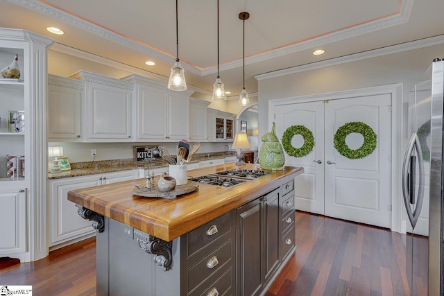 kitchen with wooden counters, appliances with stainless steel finishes, white cabinets, and dark wood-style flooring