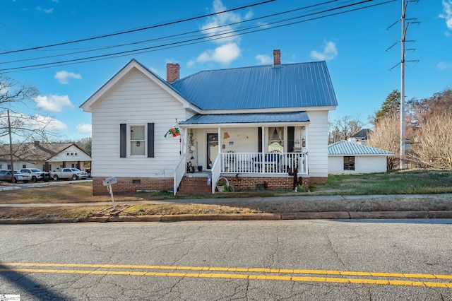 bungalow with a front yard, a porch, a chimney, crawl space, and metal roof