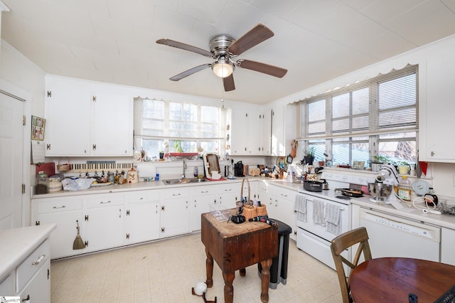 kitchen with white cabinets, white appliances, light countertops, and a sink