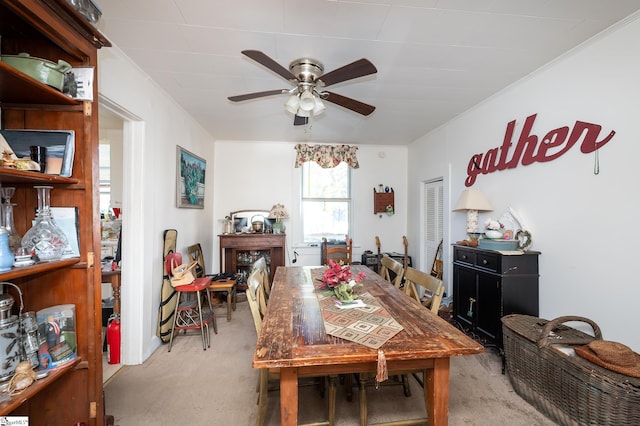 dining area featuring crown molding, light colored carpet, and ceiling fan