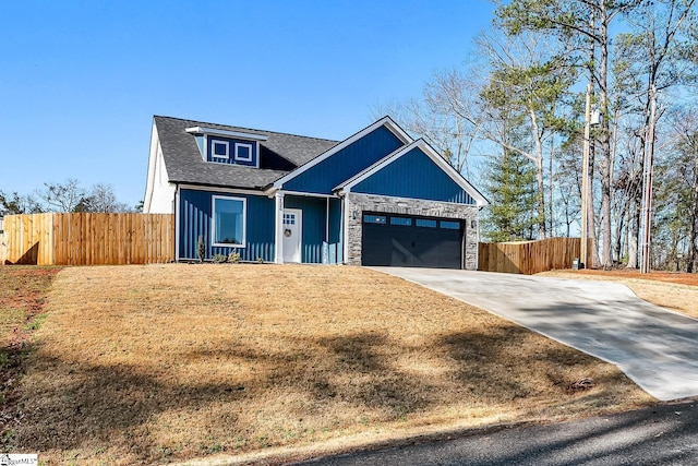 view of front of house with stone siding, an attached garage, concrete driveway, and fence