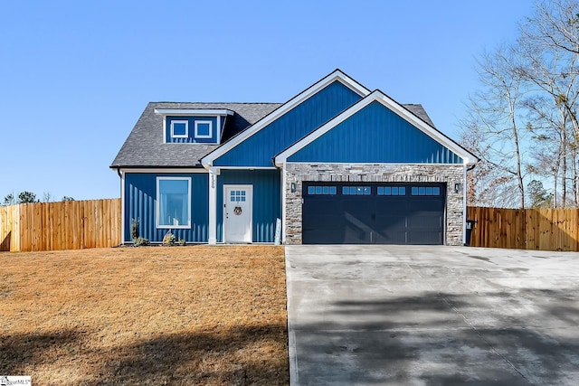 view of front of house with concrete driveway, an attached garage, fence, and stone siding