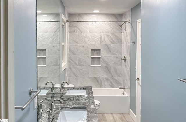 bathroom featuring toilet,  shower combination, and a sink