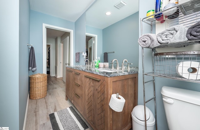 full bathroom with toilet, wood finished floors, visible vents, and a sink